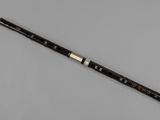a close up of a flute with a wooden handle on a gray surface
