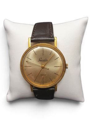 une photo d'une montre en or posée sur un oreiller