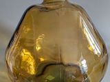 a yellow glass vase with a green apple inside of it
