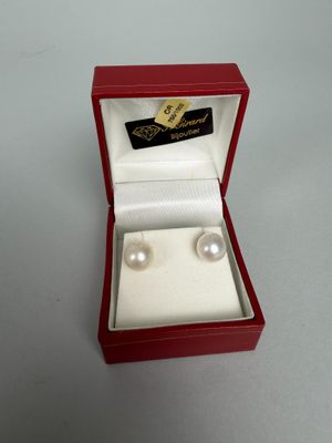 pair of white pearls in a red box on a white surface