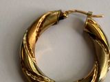a close up of a gold hoop earring on a white surface