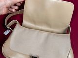 someone is holding a beige purse with a black handle on a red surface
