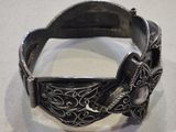 a close up of a silver bracelet with a bird on it