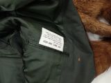 a brown dog laying on a bed with a green jacket