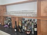 Des bouteilles et des verres sont alignés sur une étagère dans une cuisine.