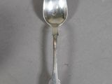 a silver spoon with a spoon handle on a table