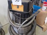 un aspirateur posé dans une pièce, sur lequel est accrochée une pancarte
