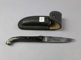a knife that is laying next to a leather case