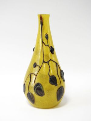 un vase jaune orné de feuilles noires