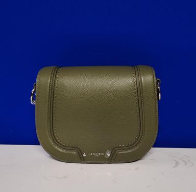 un petit sac à main vert posé sur un comptoir blanc