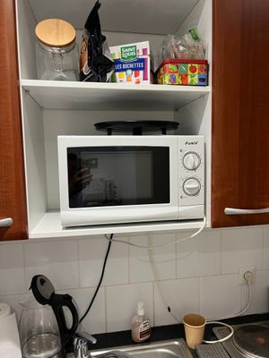 a microwave that is above a sink in a kitchen