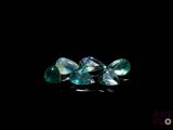 three green and blue gems on a black background