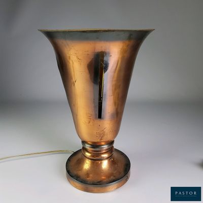 a gold vase that is on a table with a cord