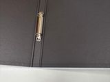 a black binder with a gold handle on top of a desk