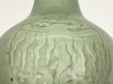 a green vase sitting on a table next to a red vase