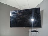 une télévision à écran plat fixée au mur au-dessus d'une étagère