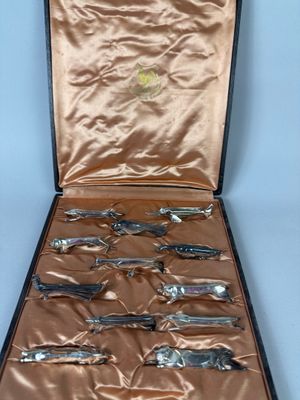six silver spoons in a case on a table