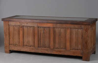 un vieux coffre en bois avec un couvercle en verre, posé sur un sol gris