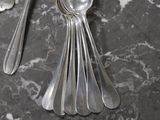 several silver spoons and spoon rest on a marble counter top