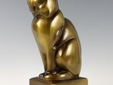 a bronze statue of a cat sitting on top of a wooden block