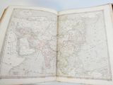 an old map of the world in an open book on a table