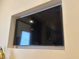 a flat screen tv mounted on the wall above a lamp