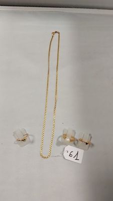 deux colliers en or et une paire de boucles d'oreilles posés sur une table