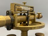 un très vieux télescope en laiton posé sur un socle, avec des pièces de monnaie