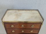 an antique chest of drawers with a marble top and brass trim