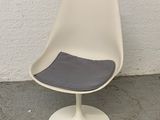une chaise blanche avec une assise grise posée sur un sol en béton