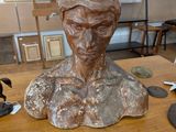 a statue of a man sitting on a table next to a pair of scissors