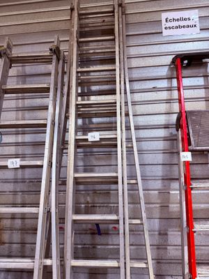 Plusieurs échelles sont alignées contre le mur d'un immeuble