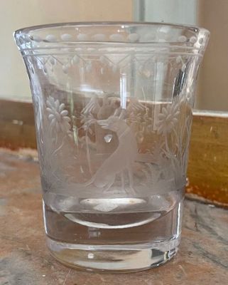 a glass cup sitting on a table with a mirror in the background