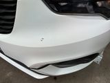 the front end of a white car with a black grille