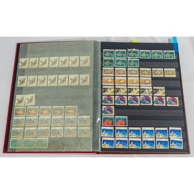 un livre ouvert, sur lequel sont posés des timbres, posé sur une table