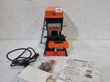 une machine orange et noire posée sur une table blanche