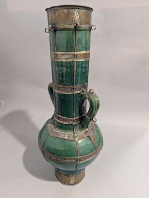 un vase vert orné d'un oiseau sur fond blanc