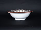 a white bowl with a red rim on a black table