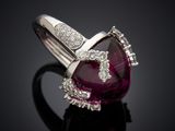 a close up of a diamond and ruby ring on a black surface