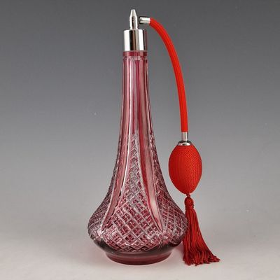 une bouteille en verre rouge avec une poignée rouge et un pompon rouge