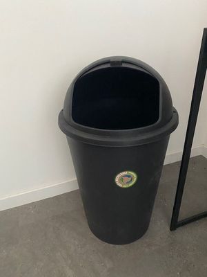 a black trash can next to a mirror on the floor
