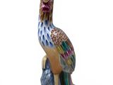 a figurine of a colorful bird sitting on a rock