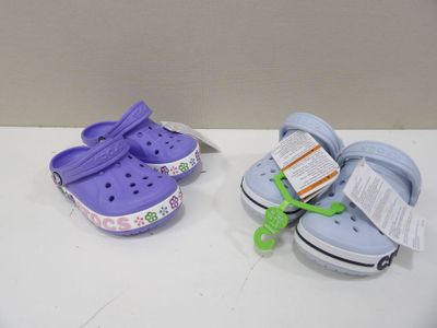 two pairs of crocs are sitting on a white table