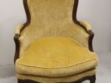 une vieille chaise avec un coussin rembourré jaune et une structure en bois