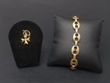 a gold chain bracelet with a star charm and a black pillow