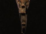 a wooden sculpture of a head on a stand with a black background