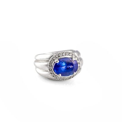 a close up of a ring with a blue stone surrounded by diamonds