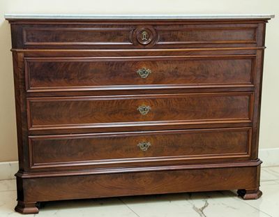 a wooden dresser with marble top in the corner of a room