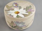 a small round box with a flower painted on it
