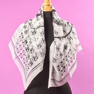 une écharpe blanche ornée de fleurs noires et roses, posée sur un mannequin
